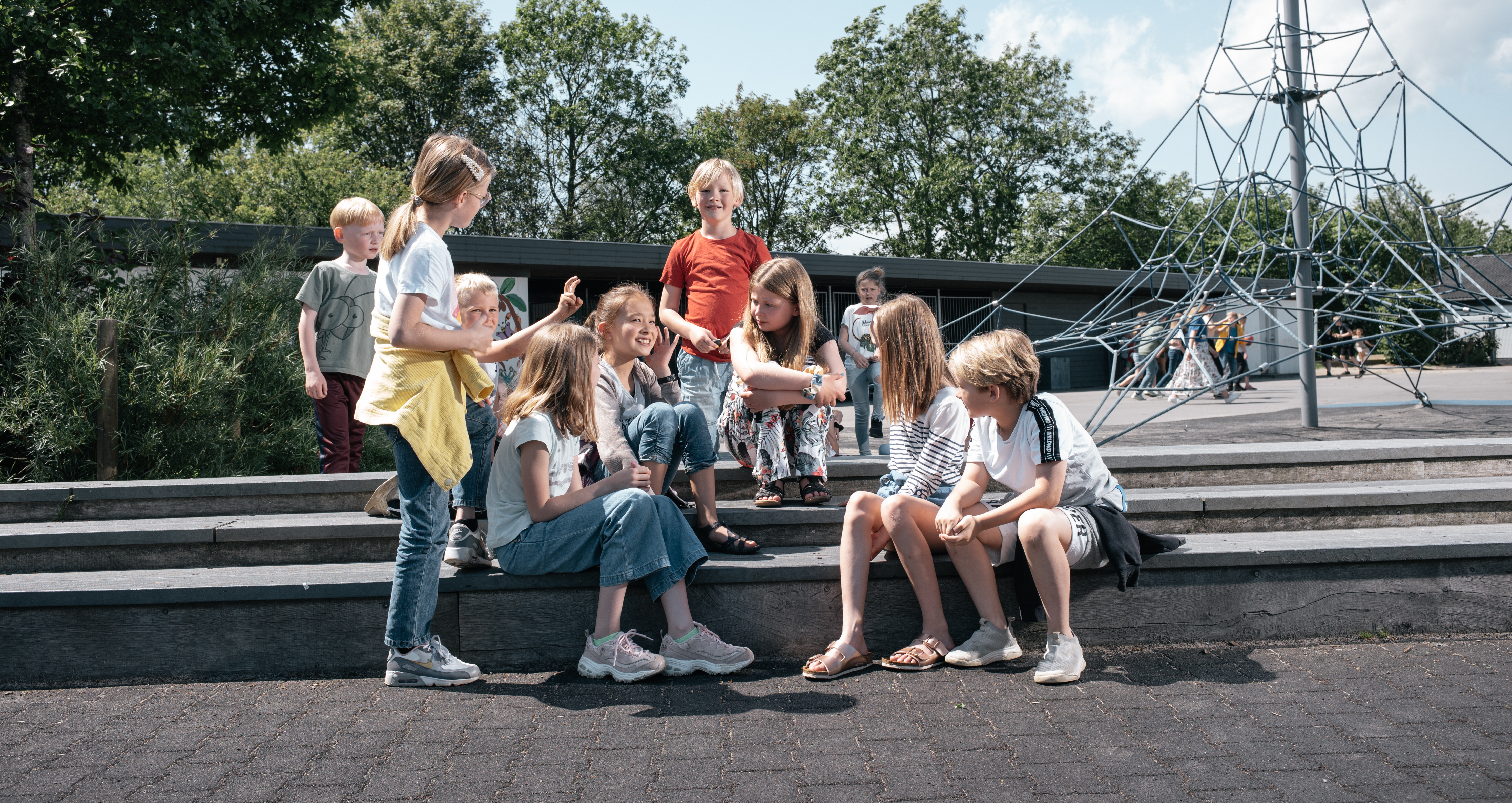 Billeder af elever i skolegården, siddende ved foldboldbanen